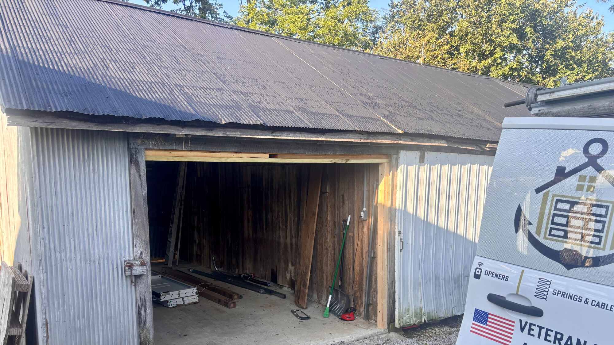 An old barn with corrugated metal siding and an empty doorway framed in new timber, before the door went in.