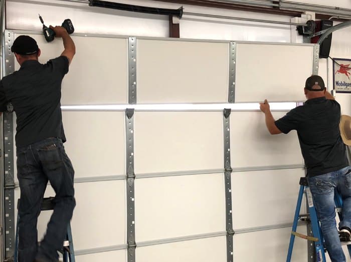 Two Anchored installers fitting a garage door panel