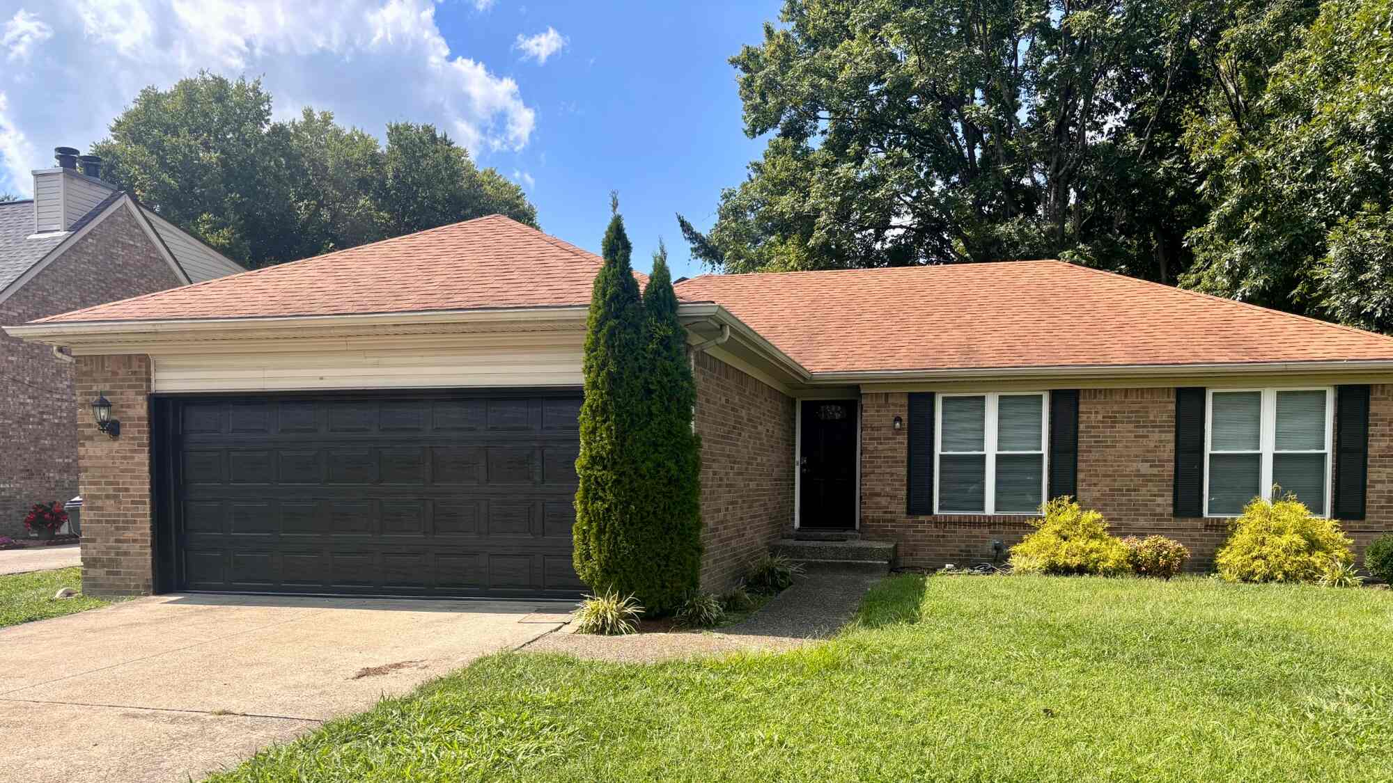 A finished dark garage door on a brick home, shot from the street.