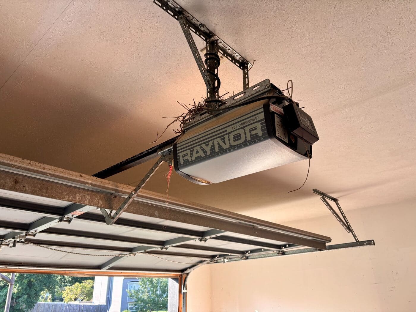 An existing chain-drive opener on the ceiling rail above a garage door.