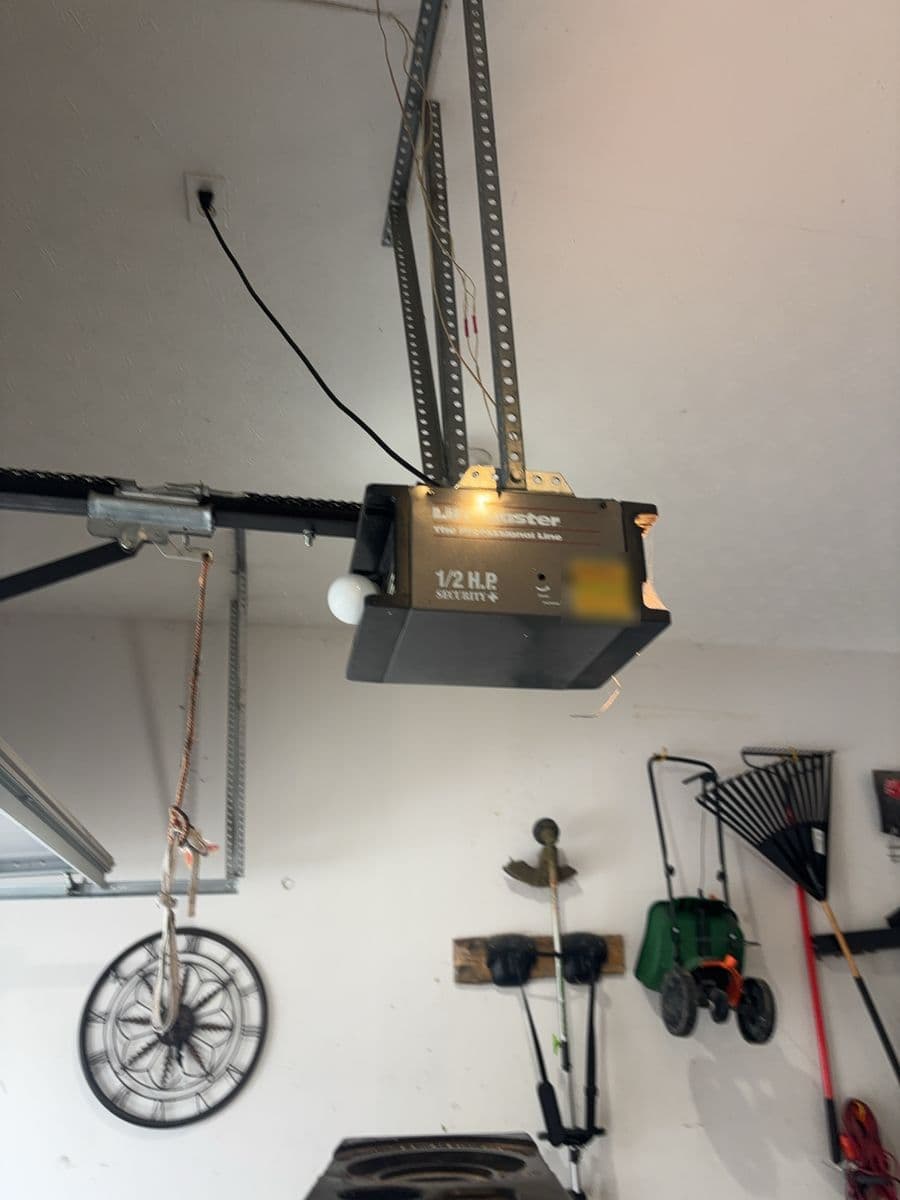 An old half-horsepower opener with a bare bulb on its ceiling brackets.