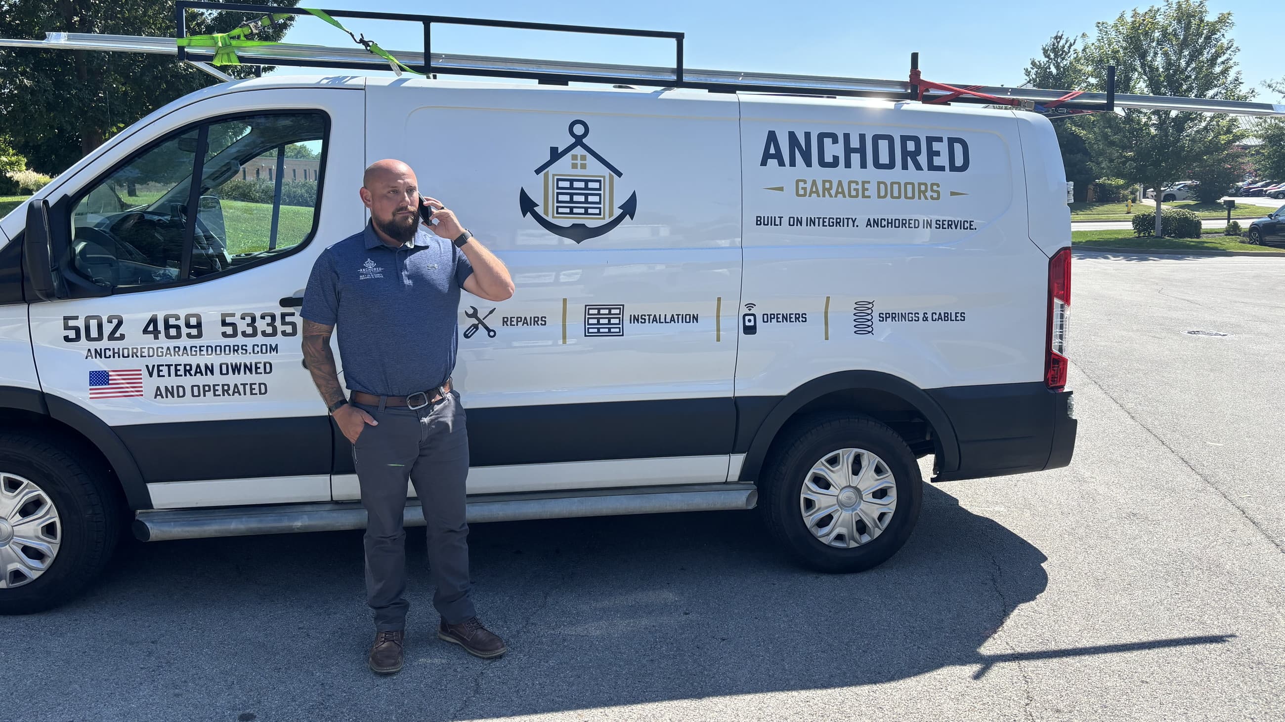 Tyler White on the phone beside the Anchored Garage Doors van